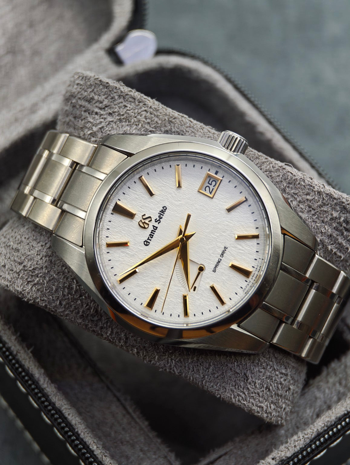 Grand Seiko SBGA259 Golden Snowflake white textured dial with gold hands and markers on a grey cushion